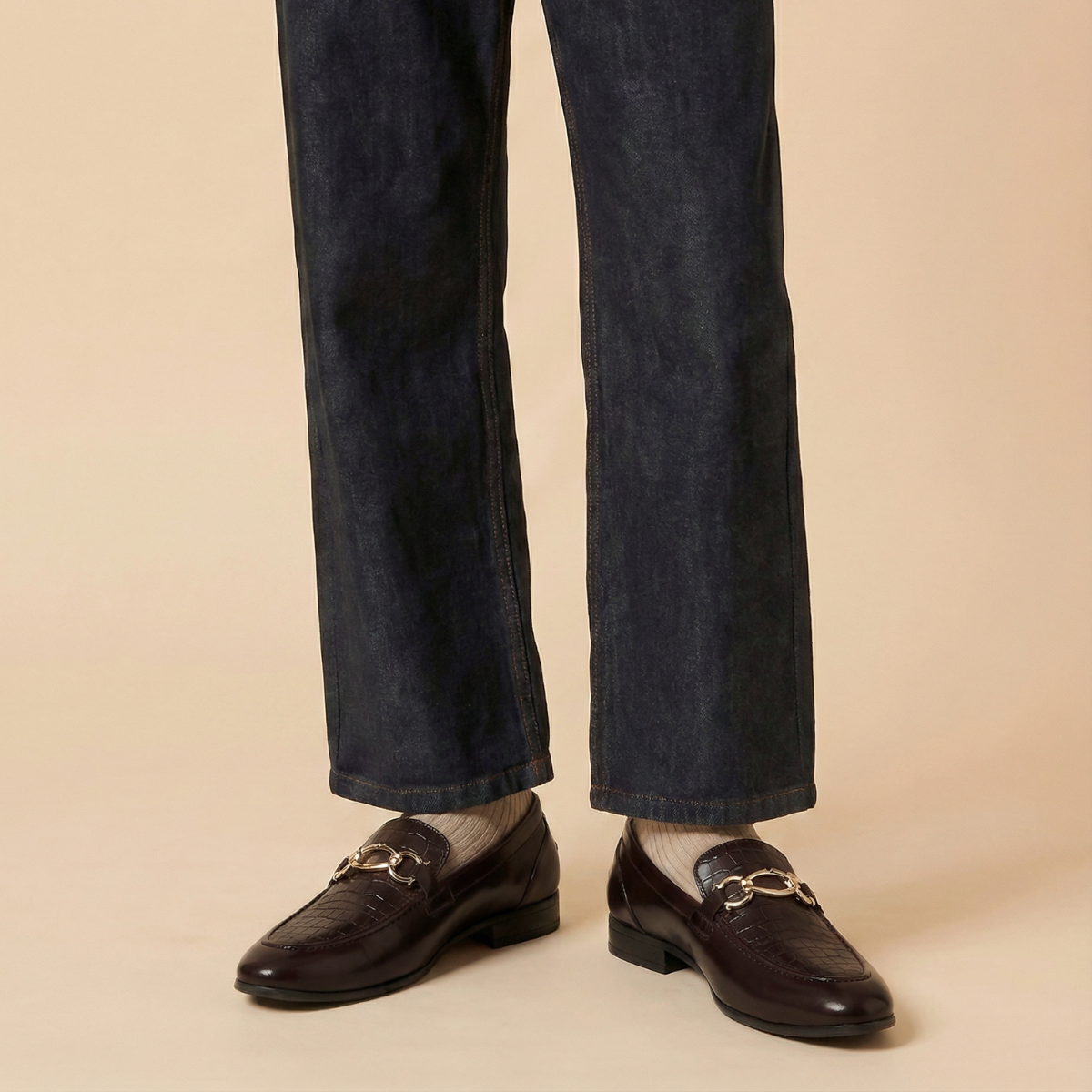 Dark blue jeans and brown loafers on a beige background