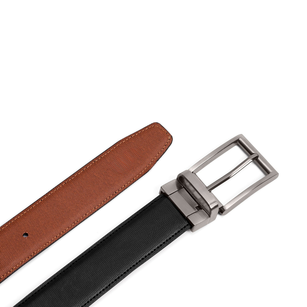 A close-up of a belt showing two sides: a black textured leather strap and a brown leather underside, with a silver-toned metal buckle on a plain white background.