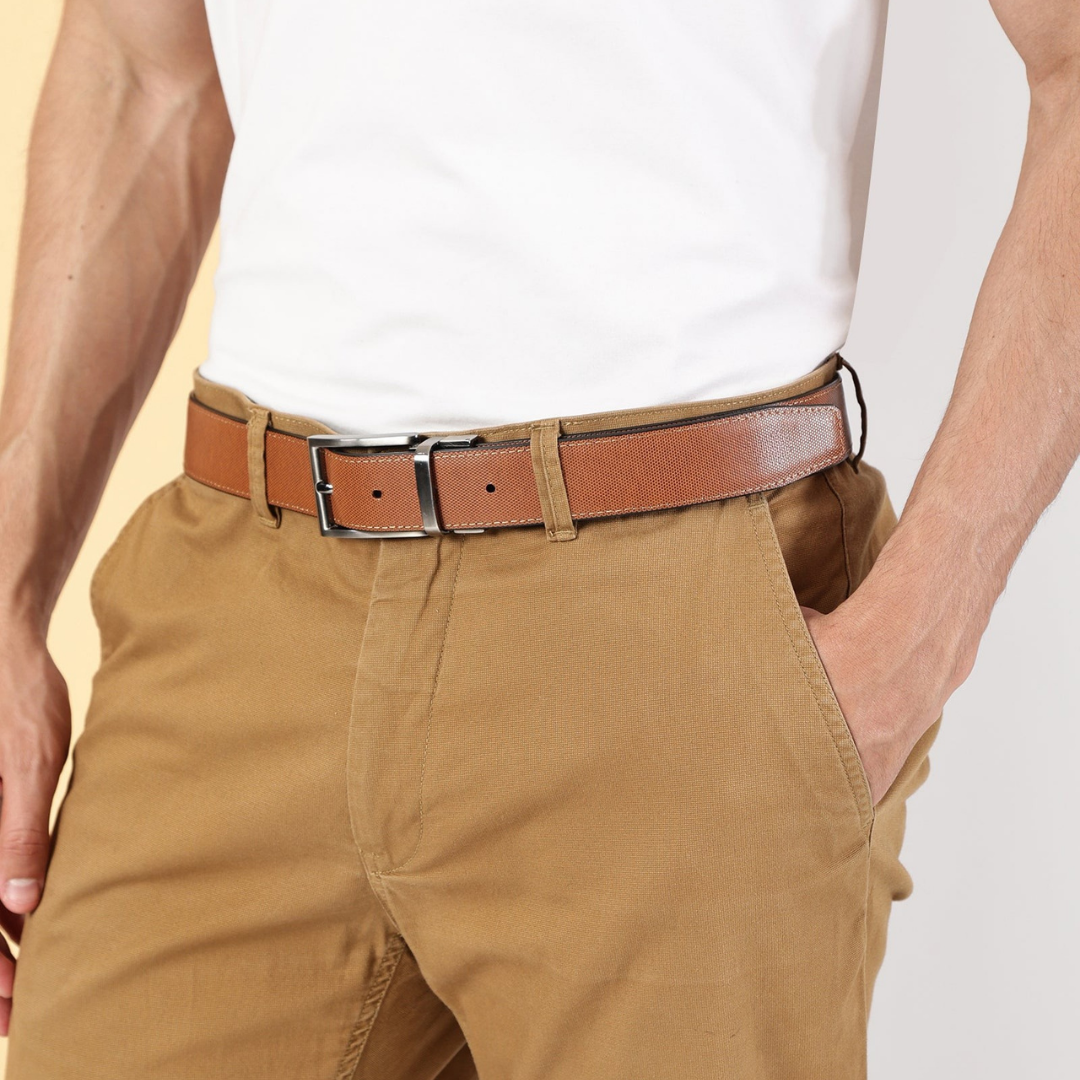 A close-up of a person wearing a tan leather belt with a silver buckle, tucked into khaki trousers and paired with a white t-shirt.
